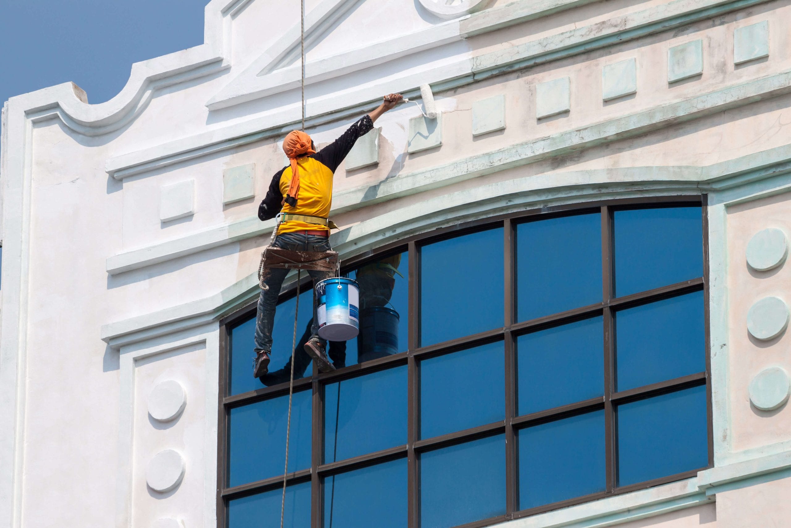 A team of professional painters working on the exterior of a commercial building in Bend, applying fresh coats of paint to revitalize its appearance.